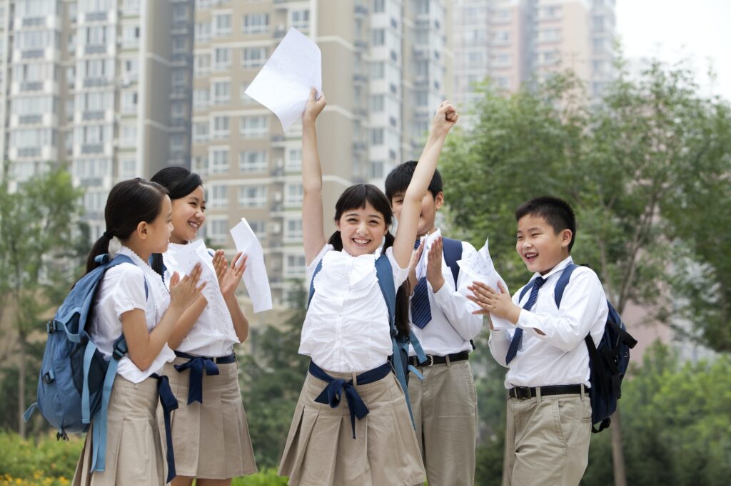 Cheerful schoolchildren in uniform celebrating for their test results