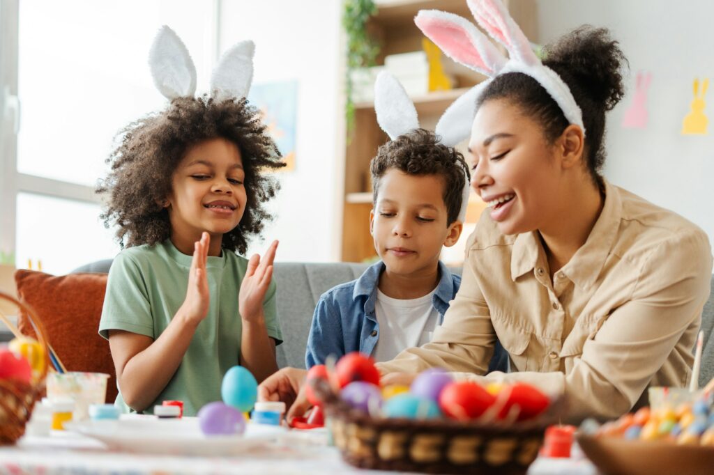 Smiling mother and kids wearing bunny ears painting easter eggs. Happy family celebration Easter