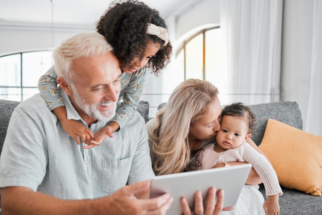 Tablet, family diversity and happy grandparents, children and baby enjoy quality time together, rel